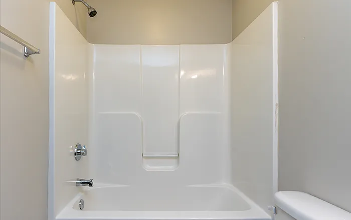 Modern, pristine white bathroom featuring a sleek bathtub and shower combination, perfect for relaxing soaks.