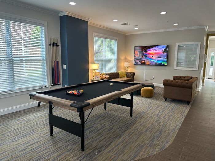 Luxurious game room featuring a sleek pool table, cozy seating area, and a large TV for entertainment.