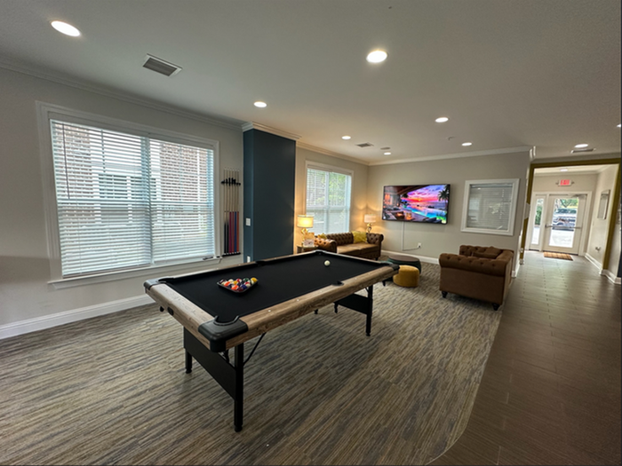 Inviting recreation room with a chic pool table, cozy seating area, and large wall-mounted TV, perfect for entertaining.