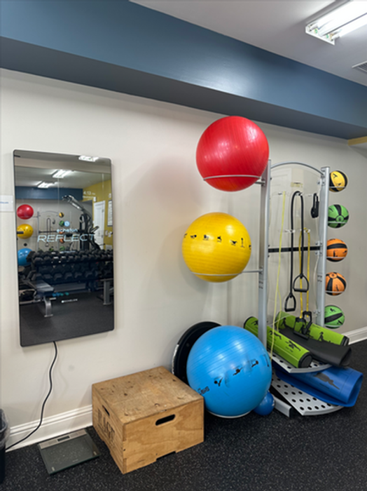 Vibrant home gym corner featuring colorful exercise balls, a sleek smart mirror, and versatile workout equipment.