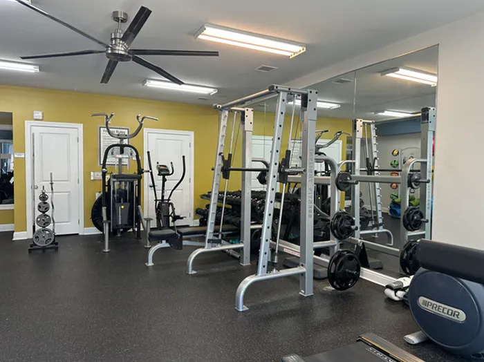 Modern fitness center with sleek exercise equipment, mirrors creating an open feel, and a vibrant yellow accent wall.