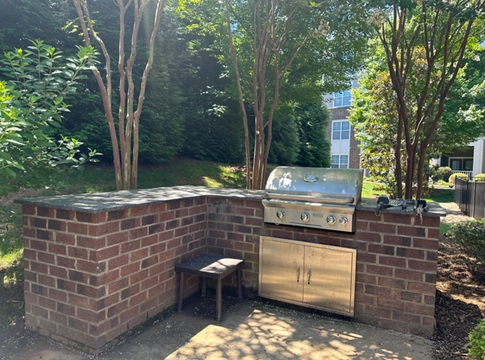 Charming outdoor grilling area with a brick-built barbecue setup surrounded by lush greenery, perfect for entertaining.