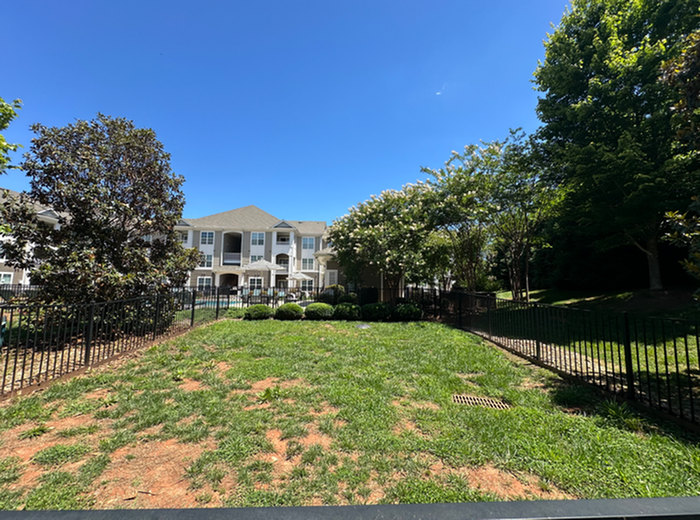 Charming apartment complex with manicured green space, vibrant trees, and a sunny sky, offering a serene living environment.