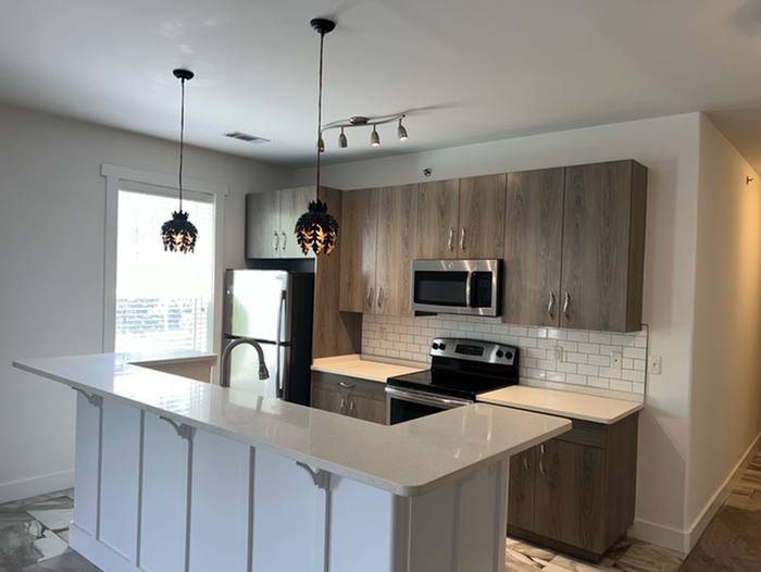 Modern kitchen design featuring sleek countertops, stylish cabinetry, and stainless steel appliances with elegant pendant lighting.