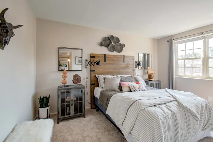 Bright and cozy bedroom with natural light, featuring elegant decor, a plush bed with striped linens, and modern art accents.