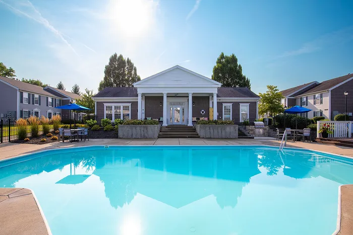 Charming apartment complex with a pristine swimming pool, surrounded by lush landscaping and modern architecture, perfect for relaxing under the sunny sky.