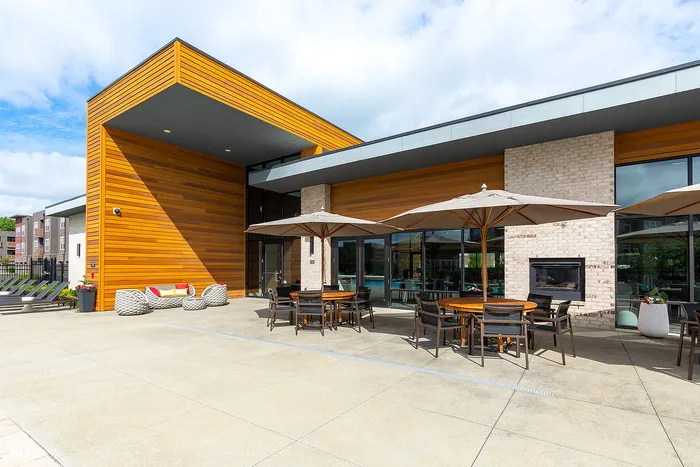 Modern outdoor terrace with stylish wood paneling, cozy seating, and elegant umbrellas, perfect for relaxation.