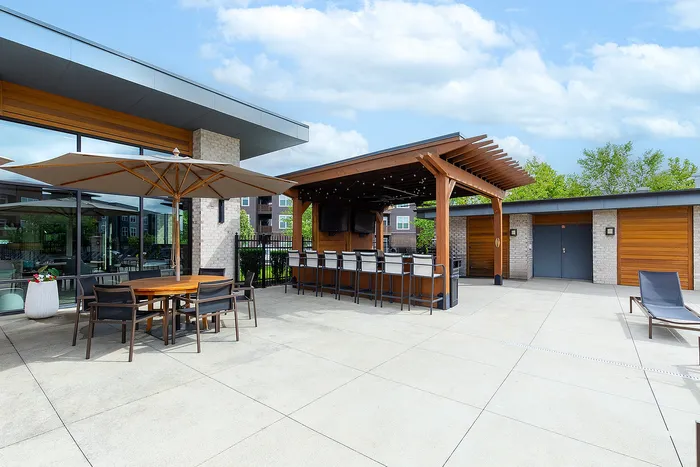 Modern outdoor patio with shaded seating, sleek bar area, and stylish pergola, offering a perfect space for entertainment and relaxation.