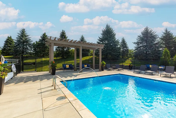 Elegant outdoor pool area with stylish lounge chairs and a charming pergola, perfect for relaxation and enjoying sunny days.