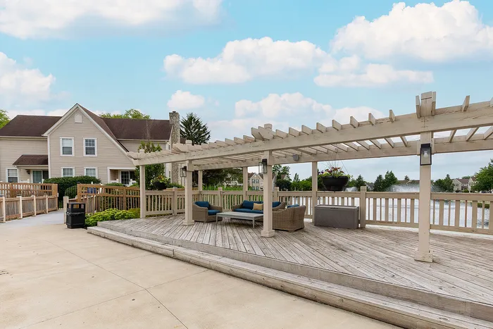 Charming outdoor patio with elegant wooden pergola, cozy seating area, and serene lakeside view.
