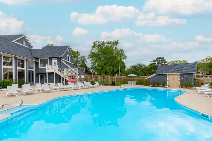 Inviting outdoor pool area with stylish lounge chairs surrounded by lush greenery and modern architecture, perfect for relaxation.