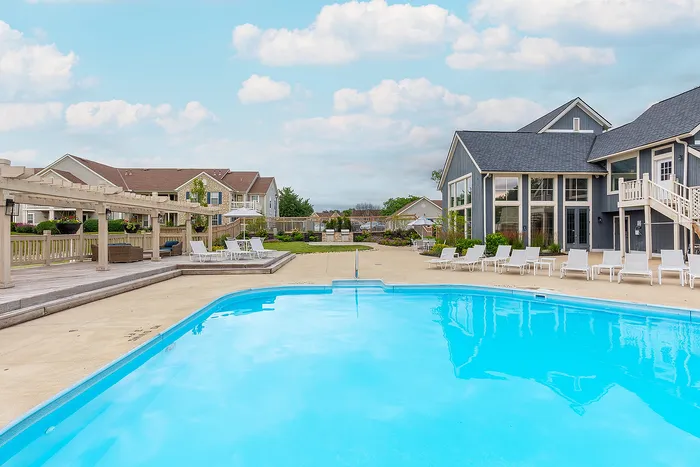 Inviting residential complex with a pristine swimming pool, surrounded by elegant lounge chairs and a charming clubhouse, offering a relaxing and luxurious lifestyle.