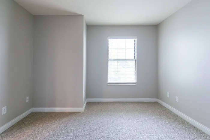 Bright, spacious bedroom with soft grey walls and a large window offering ample natural light.