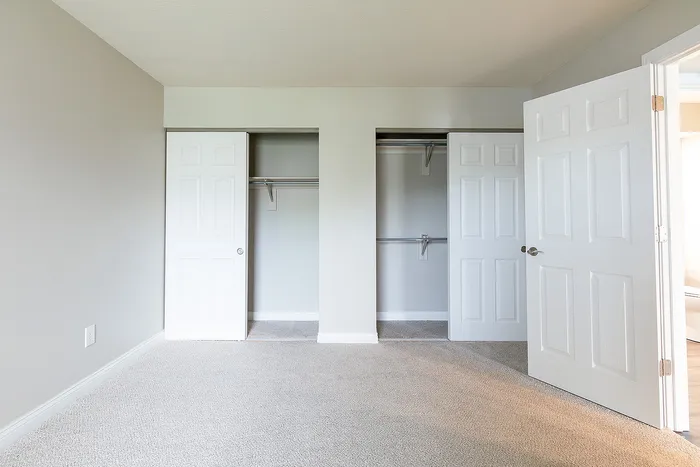 Bright and spacious room with dual closets and plush carpeting, perfect for stylish organization and comfort.