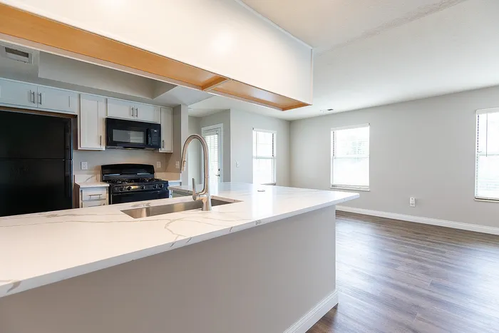 Modern open-concept kitchen with sleek marble countertops, stainless steel faucet, and integrated appliances.