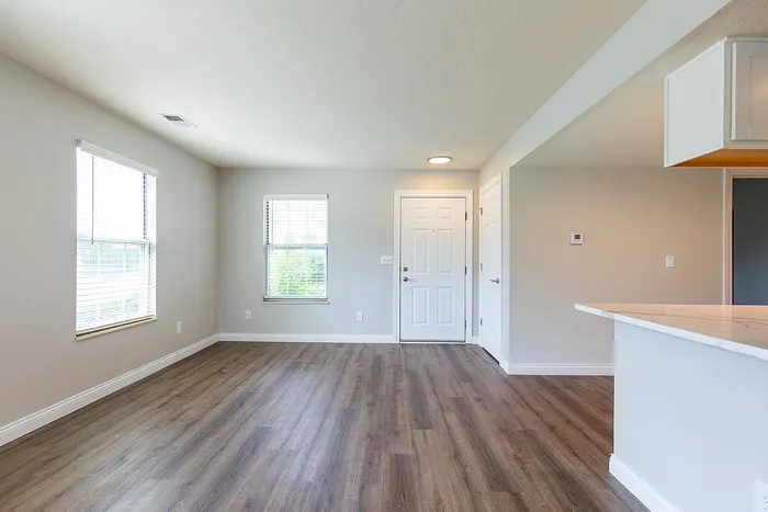 Bright and inviting modern living space with elegant wood flooring and abundant natural light, perfect for cozy gatherings.
