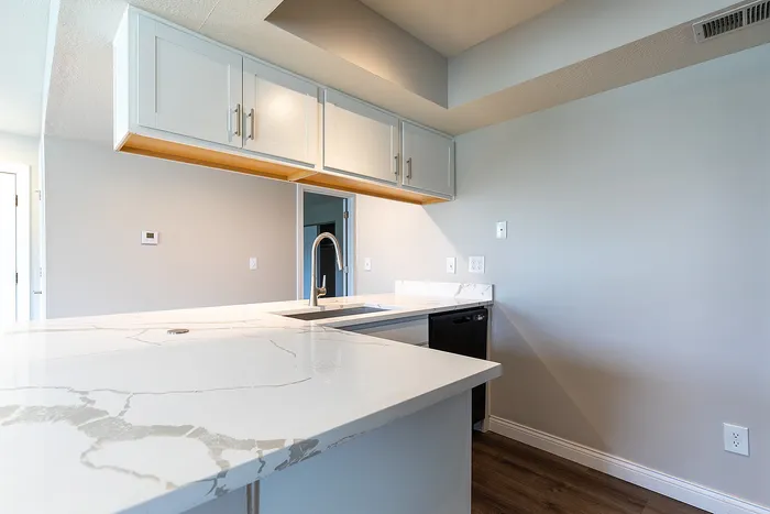 Modern kitchen space featuring sleek white cabinetry, elegant marble countertops, and a stylish stainless steel faucet.