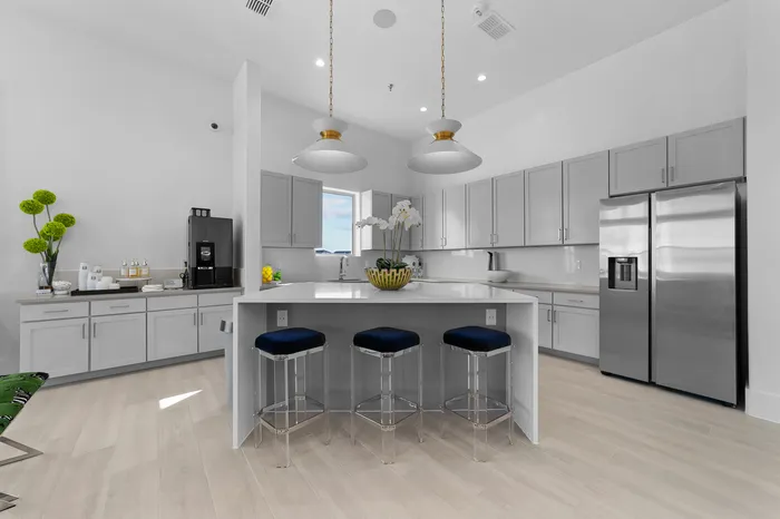 Modern community kitchen with sleek cabinetry, stainless steel appliances, and a chic island with bar seating. Complimentary coffee bar