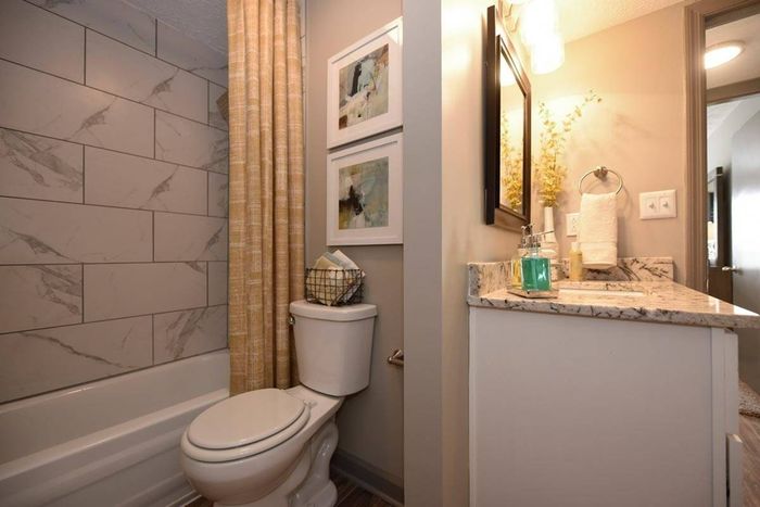 Bathroom with granite counters and marble tiling in bathtub