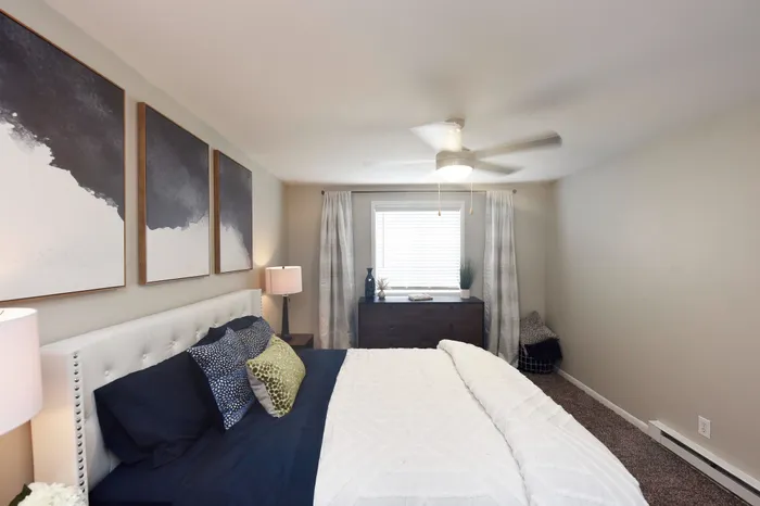 Inviting bedroom featuring a plush bed with decorative pillows, ambient lighting, and modern abstract art.