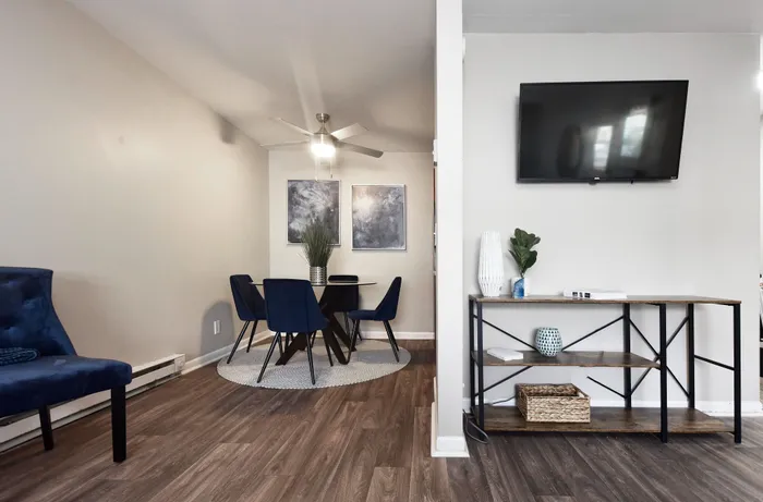 Modern dining space with elegant blue chairs, stylish art, and wall-mounted TV in a cozy living room.