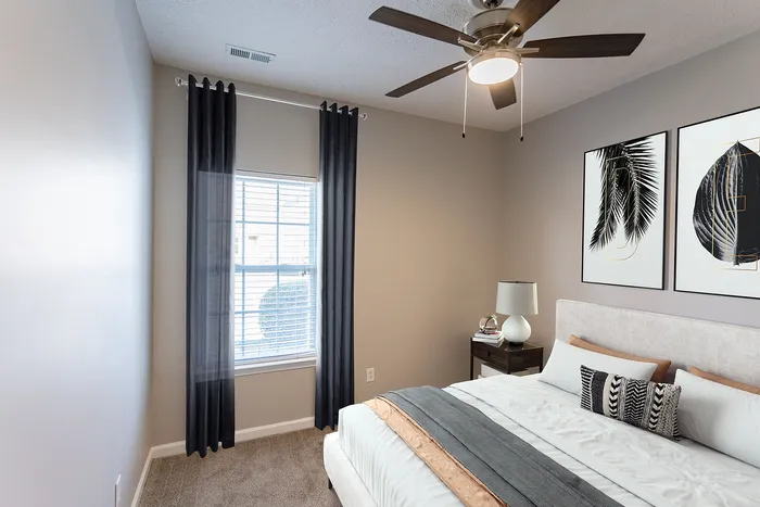 Stylish bedroom with modern decor, featuring a comfortable bed, chic artwork, and a ceiling fan.
