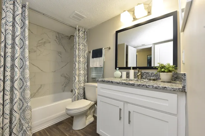 Modern bathroom with marble tile, granite countertop, and stylish shower curtain.