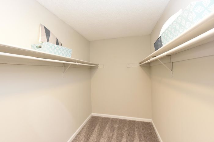 Bright walk-in closet with dual shelving and storage baskets.