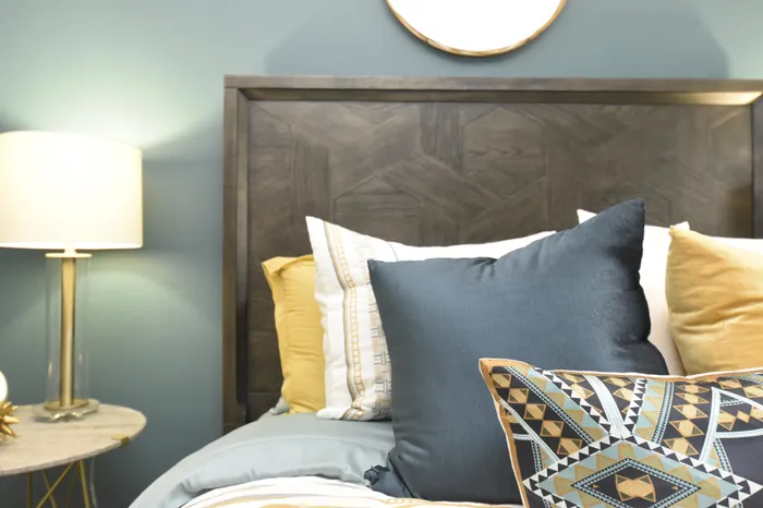 Inviting bedroom setup featuring a stylish wooden headboard, plush pillows, and a modern bedside lamp.
