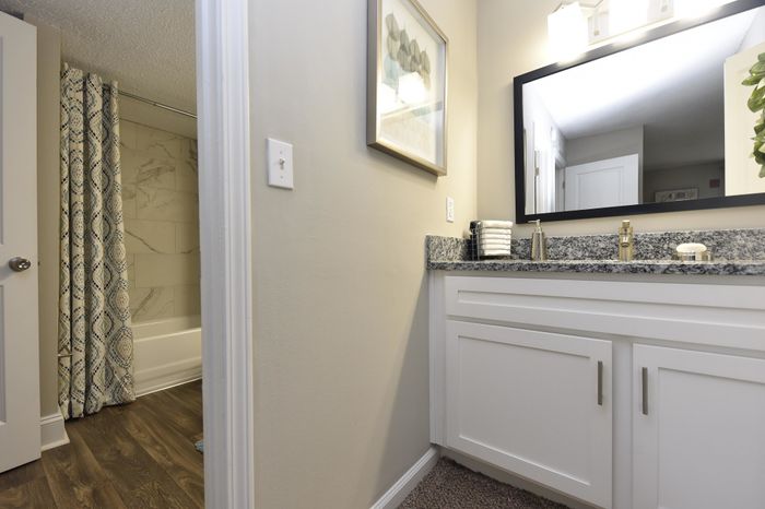 Chic modern bathroom featuring granite countertops, framed mirror, and stylish decor.