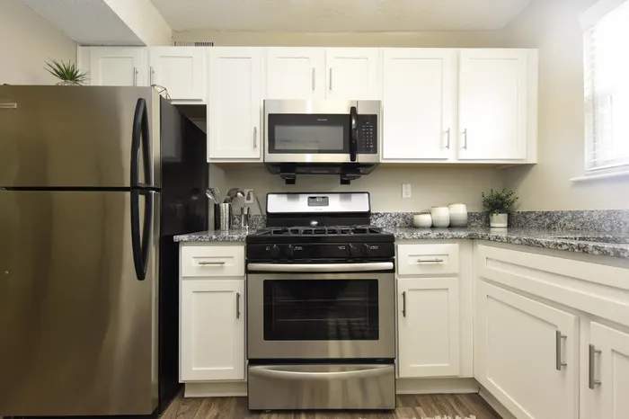 Modern kitchen featuring stainless steel appliances, white cabinets, and granite countertops.
