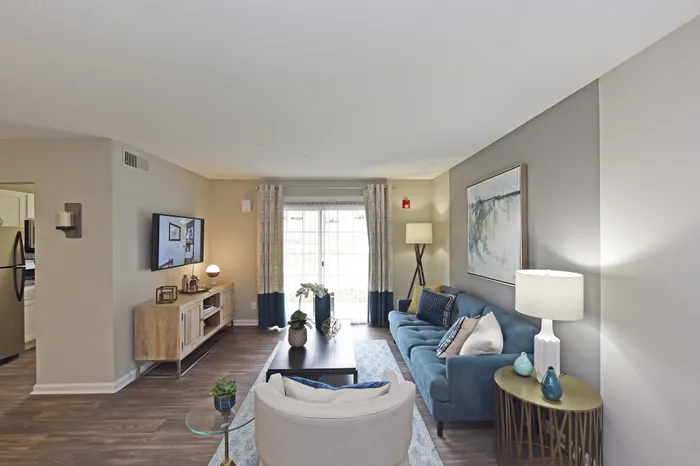 Inviting living room with stylish decor, featuring a blue sofa, modern art, and ample natural light.