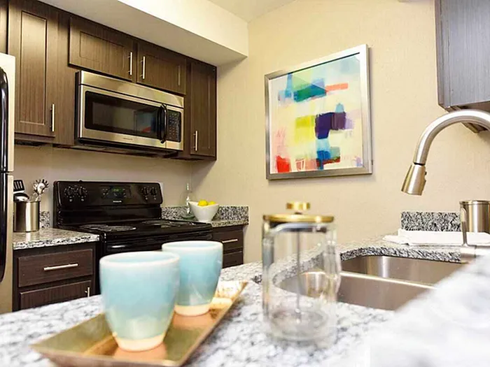 Contemporary kitchen with stainless steel appliances, granite countertops, and colorful modern art.
