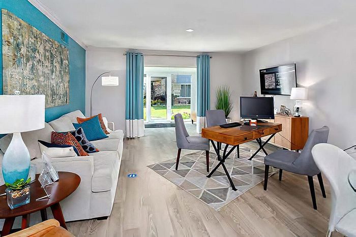 Bright and contemporary living room featuring stylish furniture, vibrant decor, and large windows with garden view.