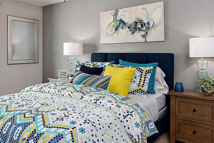 Modern bedroom showcasing a stylish bed with colorful geometric bedding and contemporary art.