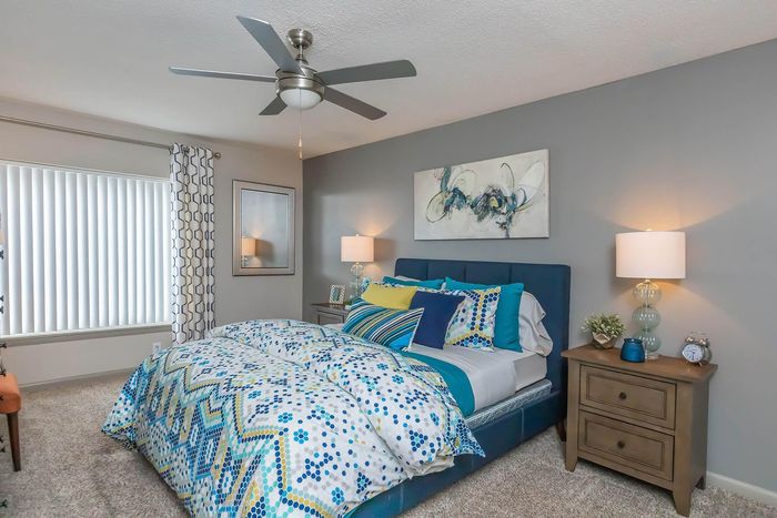 Inviting bedroom with modern decor, featuring a blue and white patterned comforter, side lamps, and stylish artwork.