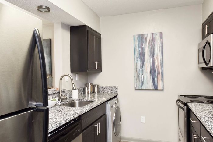 Modern kitchen with stainless steel appliances, granite countertop, and stylish artwork.