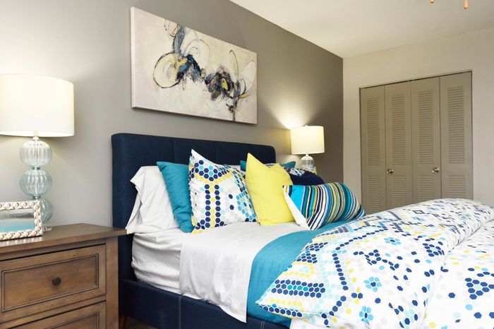 Elegant bedroom with modern decor, featuring a cozy bed with colorful geometric-patterned bedding and stylish art piece on a neutral wall.