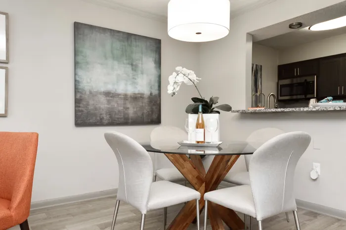 Chic dining area with glass table, stylish chairs, and elegant decor in an open-plan apartment.