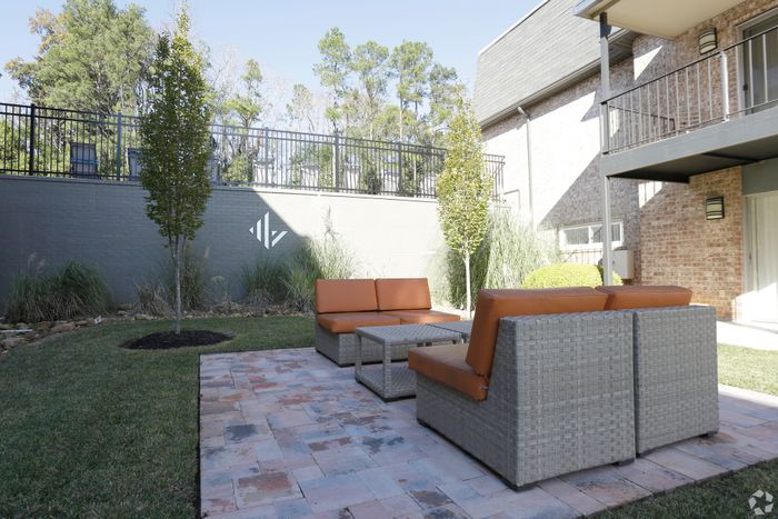 Inviting outdoor patio with modern wicker furniture surrounded by lush greenery and elegant design.