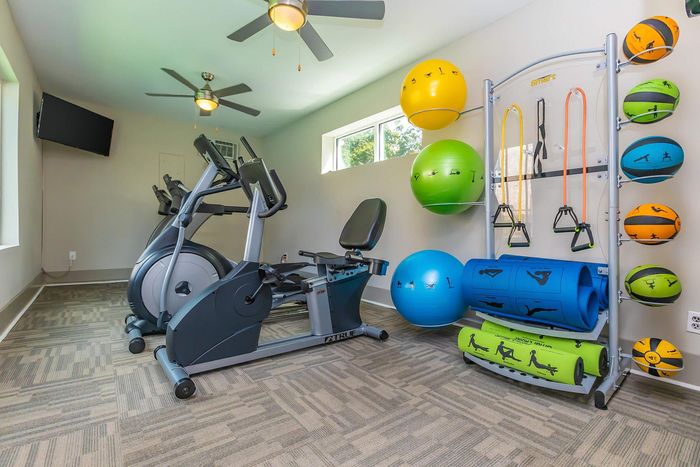 Compact apartment gym with exercise bikes, stability balls, resistance bands, and yoga mats.