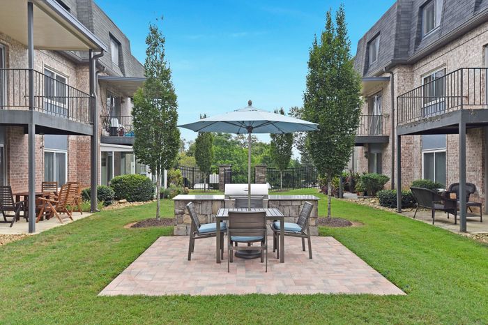 Inviting courtyard with outdoor seating and umbrella, surrounded by modern apartment balconies.