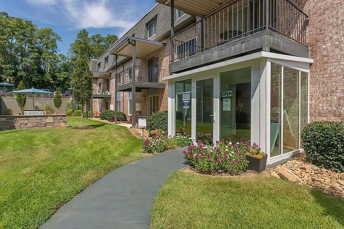 Beautiful garden apartments with balconies, green lawn, and vibrant flowers.