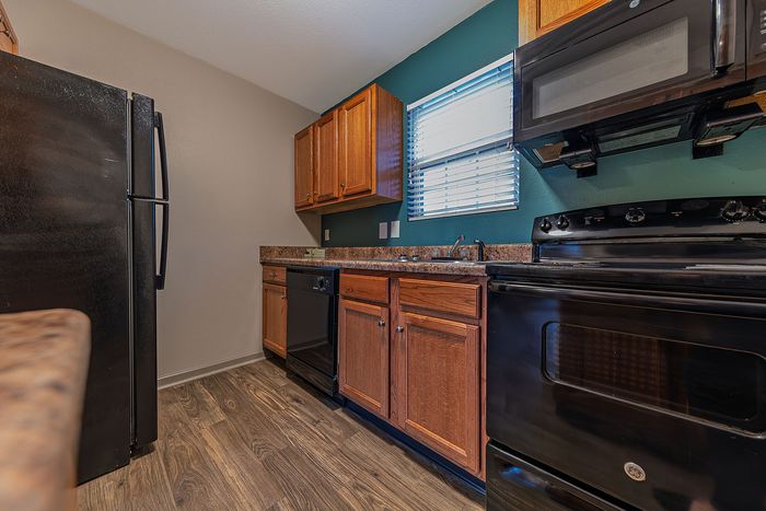 Modern kitchen featuring sleek black appliances, wooden cabinetry, and a rustic countertop.