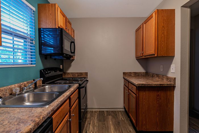 Modern kitchen with sleek countertops, wooden cabinetry, and stainless steel appliances illuminated by natural light.