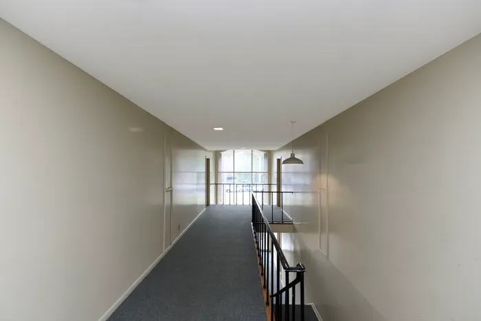 Light-filled hallway with modern design and neutral tones featuring a large window.