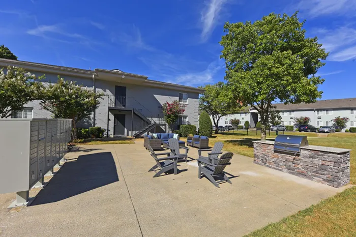 Spacious outdoor common area with comfortable seating, BBQ grill, and lush greenery.