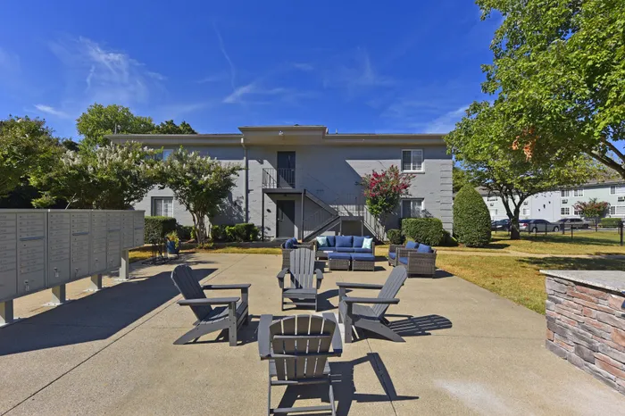 Inviting outdoor seating area with Adirondack chairs in front of a modern brick apartment building.