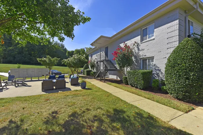 Sunny apartment exterior with cozy outdoor seating and lush greenery.