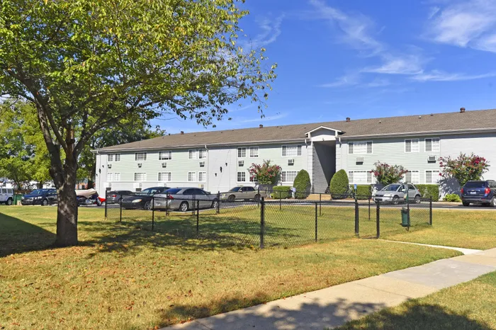 Charming apartment building surrounded by lush greenery and ample parking space.